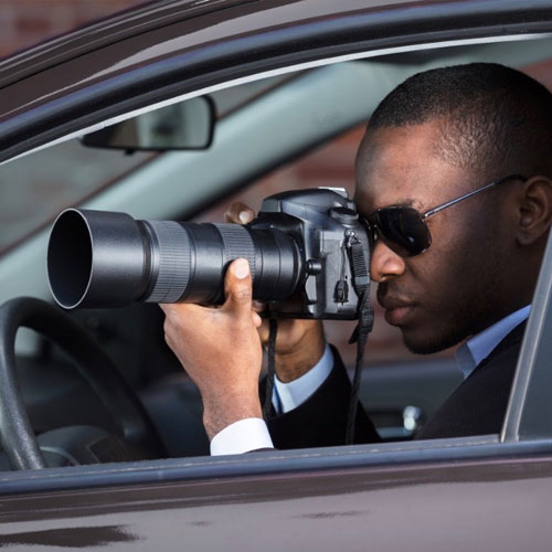 serious male undercover agent doing surveillance by binoculars and holding  paper cup of coffee Stock Photo by LightFieldStudios